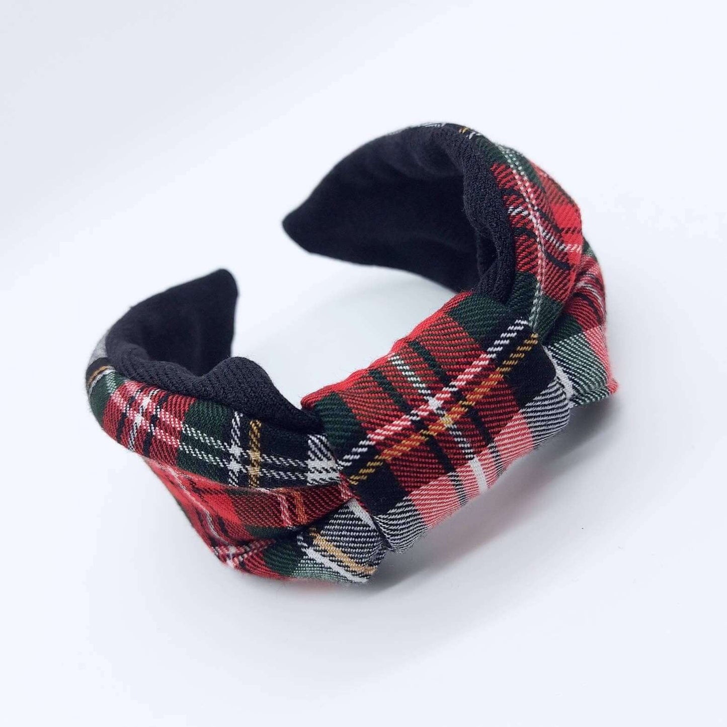 A bow-style, black and red tartan plaid fabric headband with plain black lining underneath