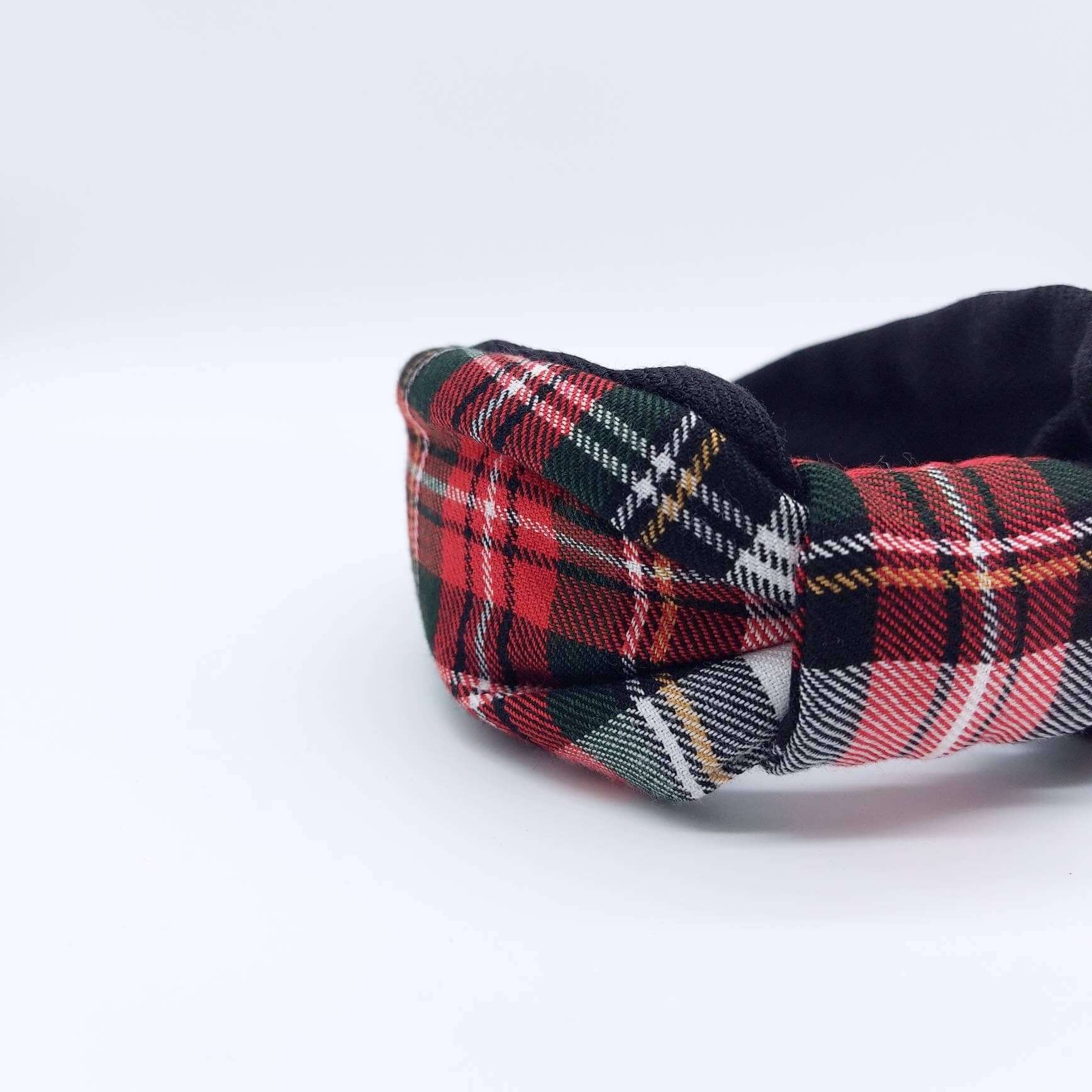 A bow-style, black and red tartan plaid fabric headband with plain black lining underneath