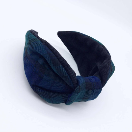 A bow-style, black and navy blue tartan plaid fabric headband with plain black lining underneath.