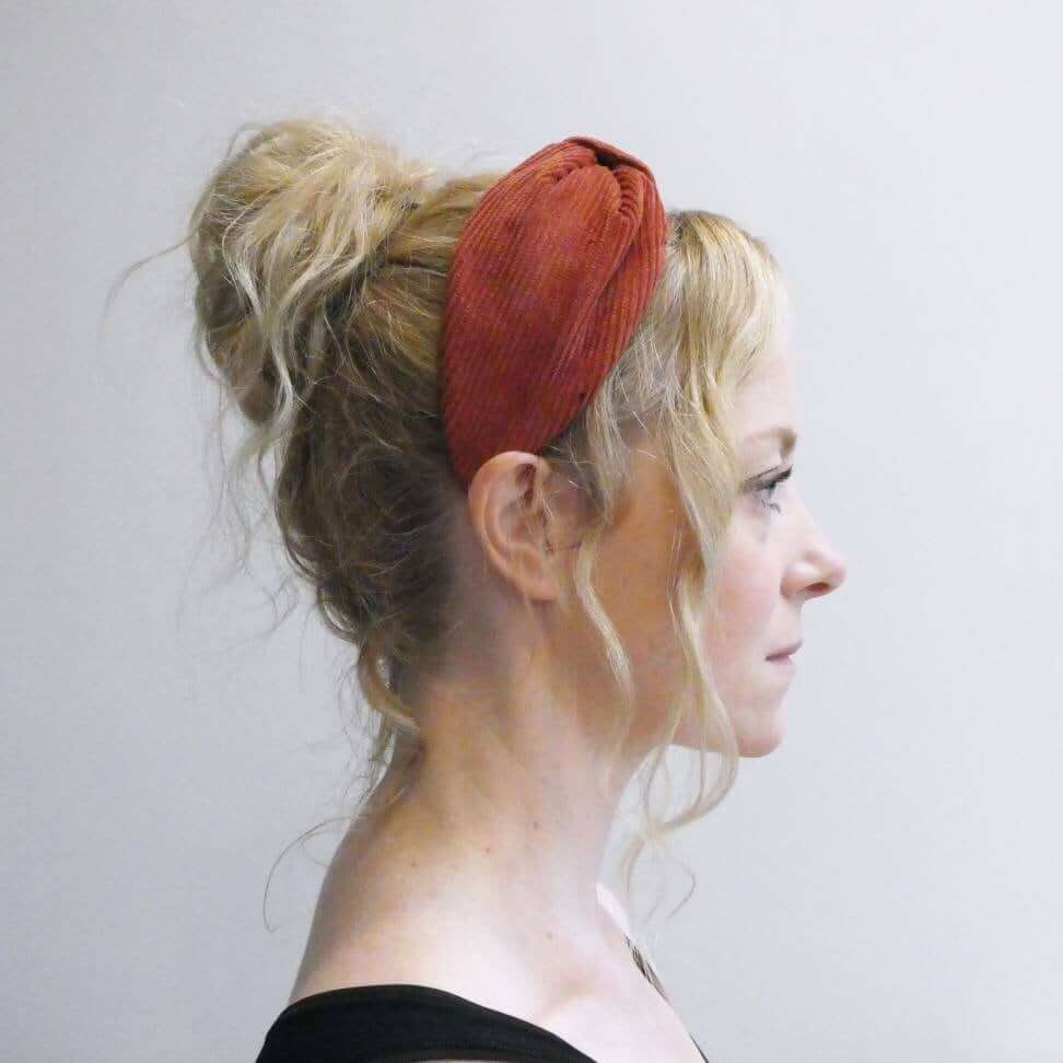 Model wears a luxury bow-style, rust-coloured thick corduroy fabric knot headband.