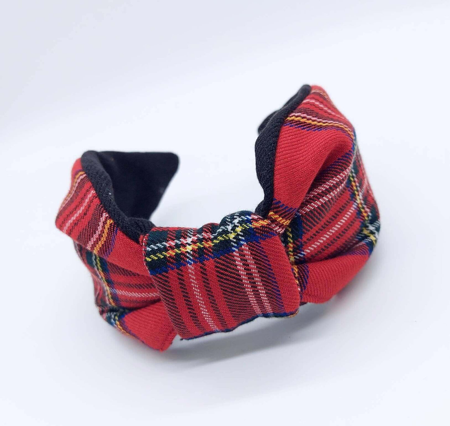 A bow-style, black and red tartan paid fabric knot headband with plain black lining underneath.