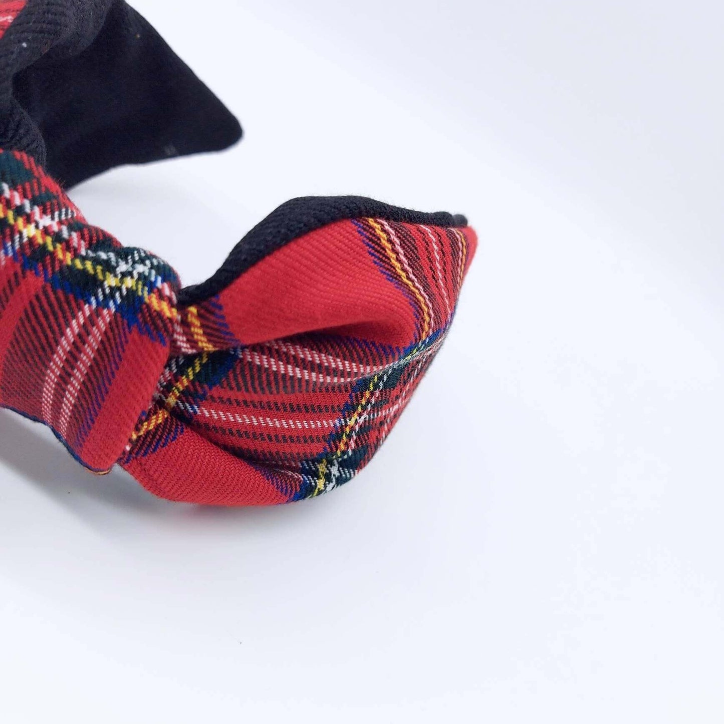 A bow-style, black and red tartan paid fabric headband with plain black lining underneath.