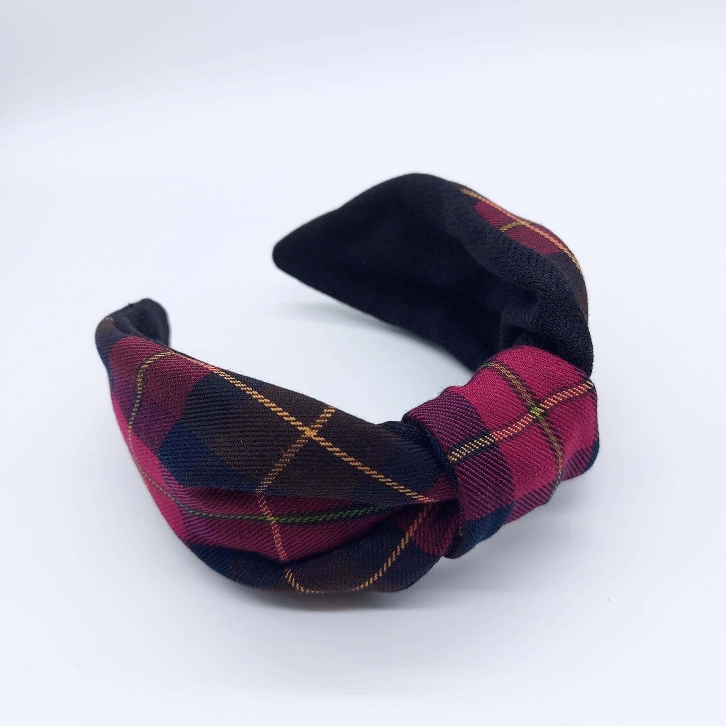 A bow-style, brown and red tartan plaid fabric knot headband with plain black lining underneath.