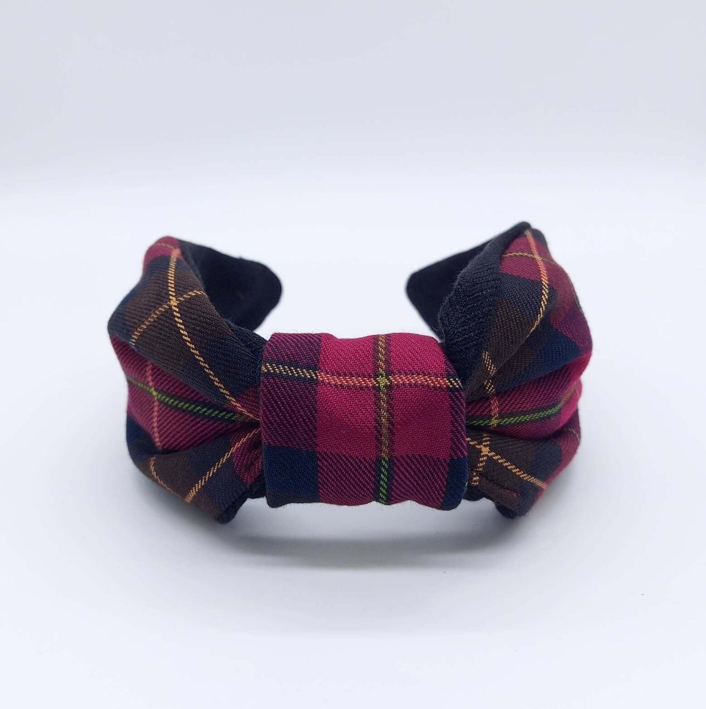 A bow-style, brown and red tartan plaid fabric knot headband with plain black lining underneath.