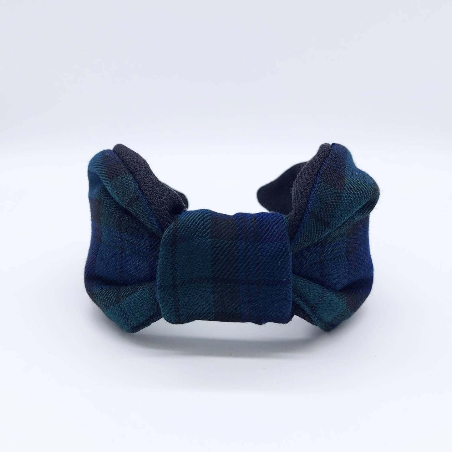 A bow-style, black and navy blue tartan plaid fabric headband with plain black lining underneath.