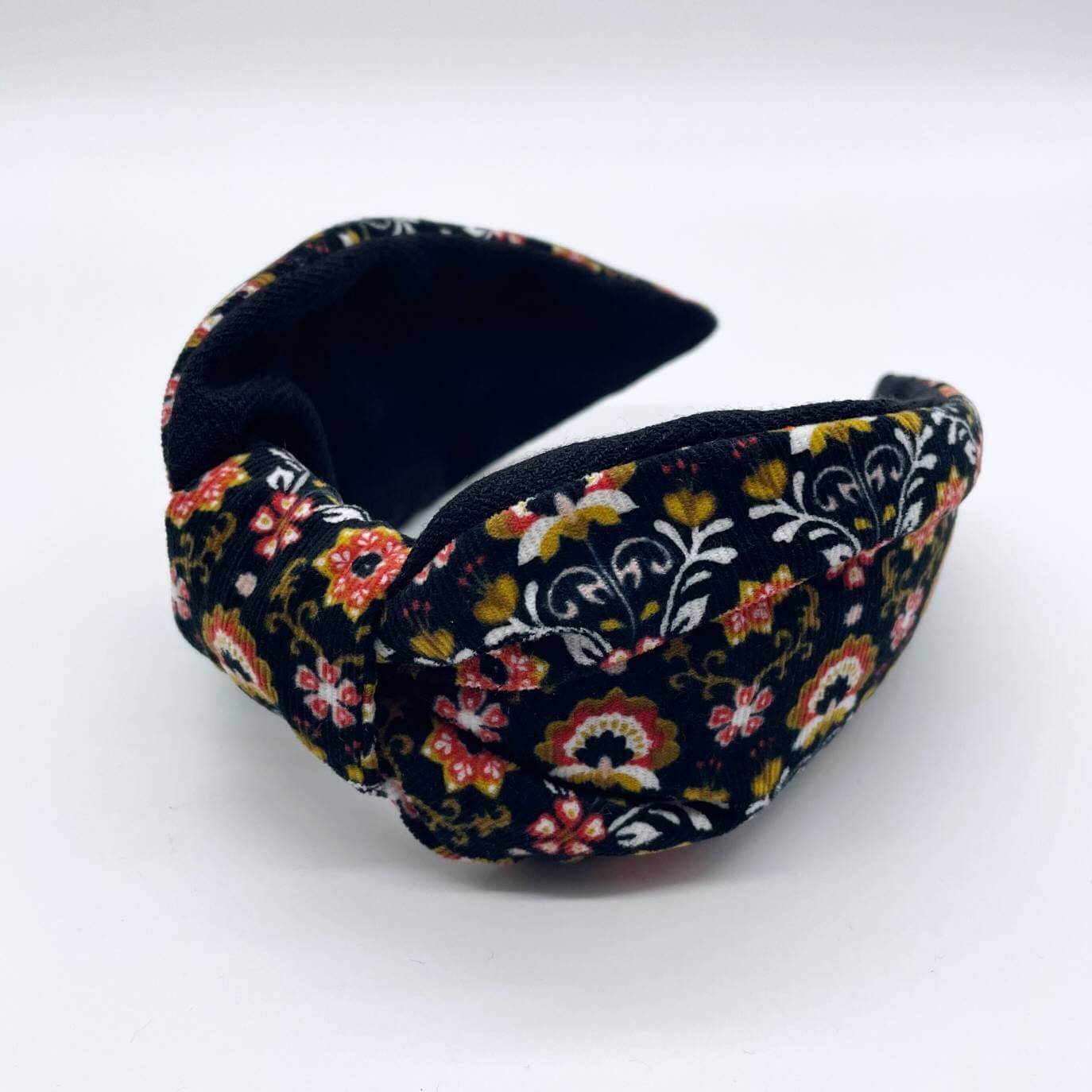 A bow-style, Scandinavian black floral-print corduroy headband with a soft, black lining underneath.