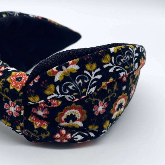A bow-style, Scandinavian black floral-print corduroy headband with a soft, black lining underneath.
