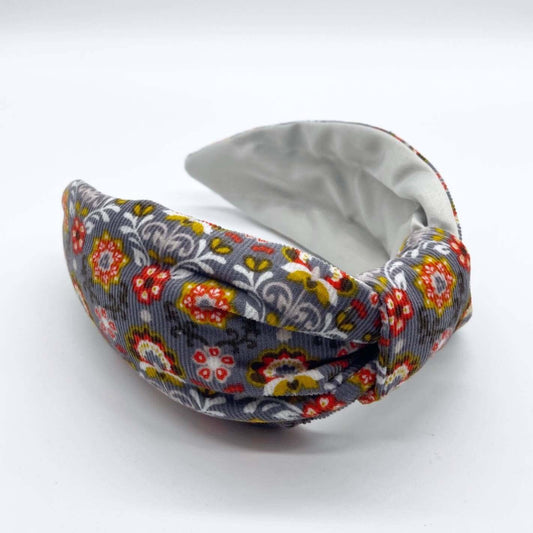 A bow-style, Scandinavian pale grey floral-print knot headband with an ice-white lining underneath.