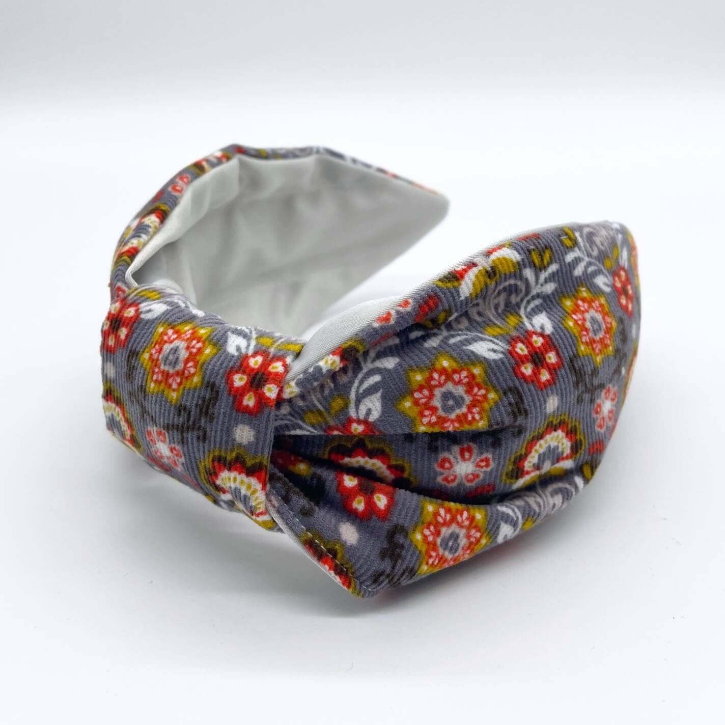 A bow-style, Scandinavian pale grey floral-print knot headband with an ice-white lining underneath.