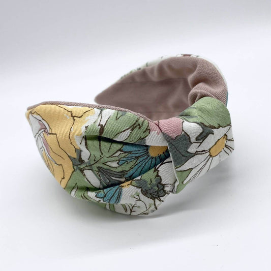 A bow-style, cream fabric headband with large pastel flowers with a soft pink lining underneath.