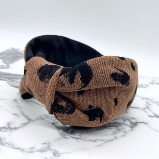 A luxury bow-style, brown and black animal print, fabric knot headband with a soft black lining underneath.
