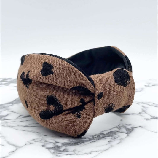 A luxury bow-style, brown and black animal print, fabric knot headband with a soft black lining underneath.